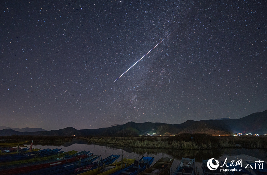 一颗火流星刺破泸沽湖的夜幕,猪槽船静静停泊,湖光山色间尽显宇宙的深邃。戴建峰摄