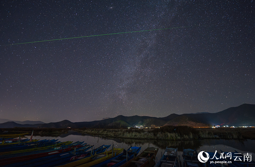 在云南丽江泸沽湖畔，繁星点点，流星与地面的光影在静谧的湖面上方交织。戴建峰摄