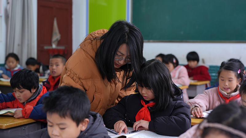 镇雄县春苗学校老师在课堂上辅导学生,拍摄于12月5日