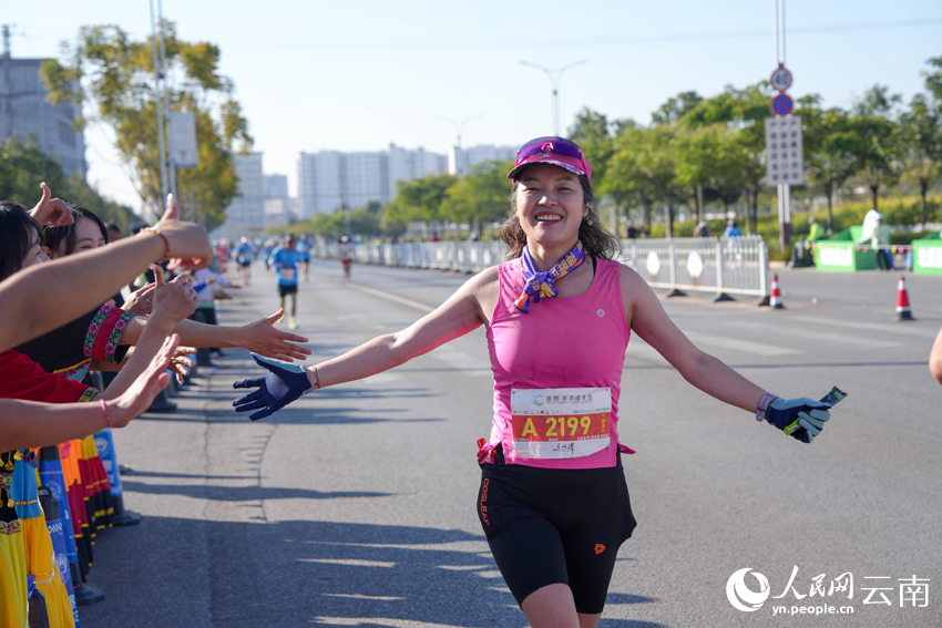 2026普洱思茅馬拉鬆跑者與啦啦隊員擊掌。人民網 王嫻攝