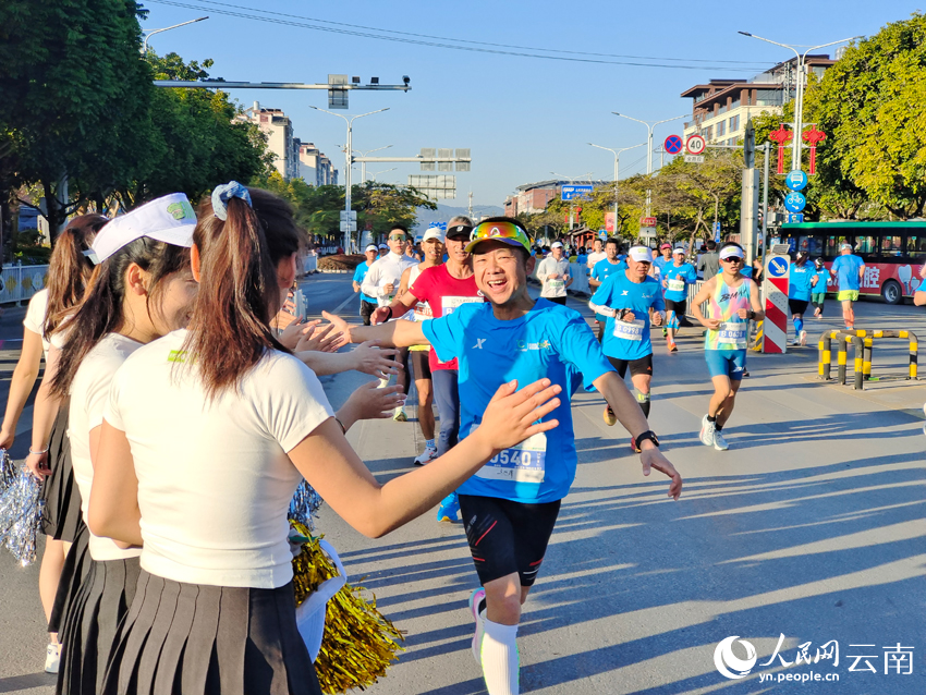 2026普洱思茅馬拉鬆跑者與啦啦隊員開心擊掌。人民網 王嫻攝