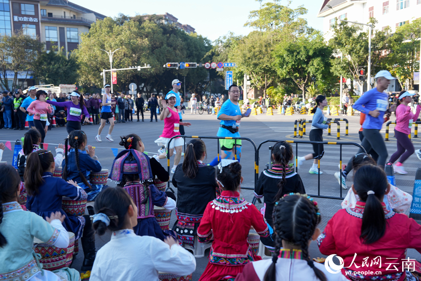 普洱小朋友身着民族服装为2026普洱思茅马拉松跑者加油。人民网 王娴摄