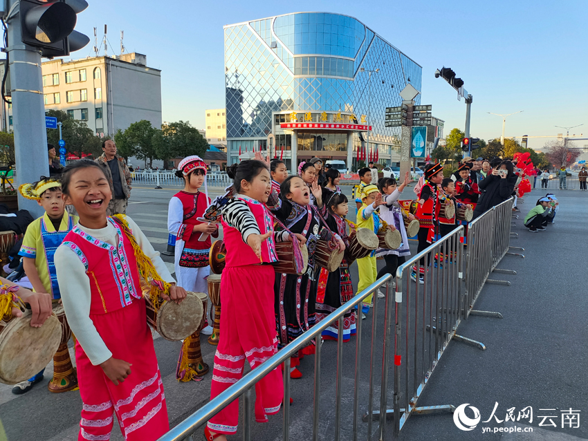 身著少數民族服飾的小朋友正用象腳鼓為2026普洱思茅馬拉鬆跑者加油。人民網 王嫻攝