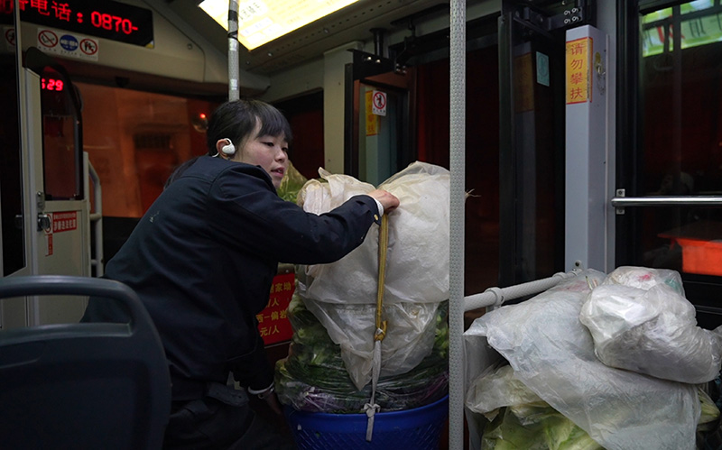 司机王丽帮助菜农上下车。