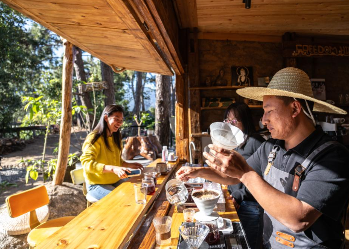 咖啡師(右)在雲南省臨滄市臨翔區邦東鄉昔歸村昔歸咖啡庄園為顧客制作咖啡。圖源:新華社