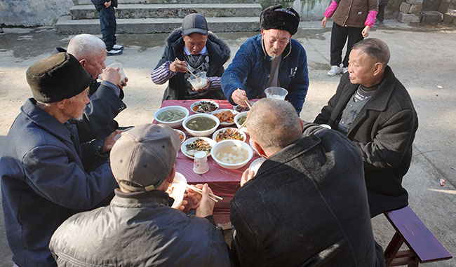 当地老人正在品尝美味的“年猪饭”。
