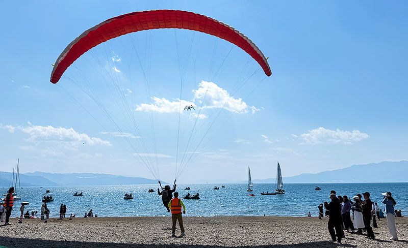 游客在抚仙湖畔体验滑翔伞。马智摄