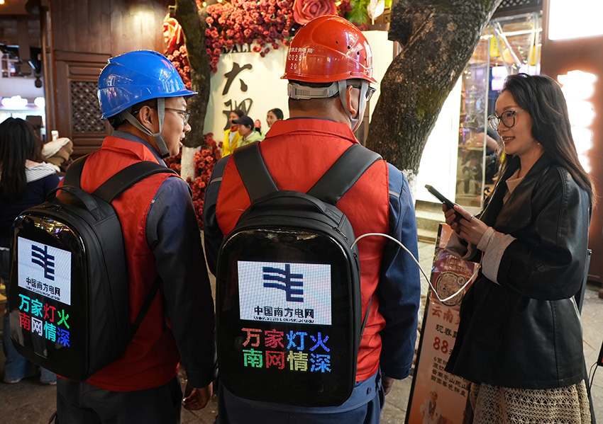 9.春節期間,南方電網雲南大理供電局黨員服務隊隊員使用背包電源為大理古城游客進行手機充電。這種背包電源可在突發停電、自然災害或重大活動保電中提供臨時應急供電。(沙子鍵 攝)