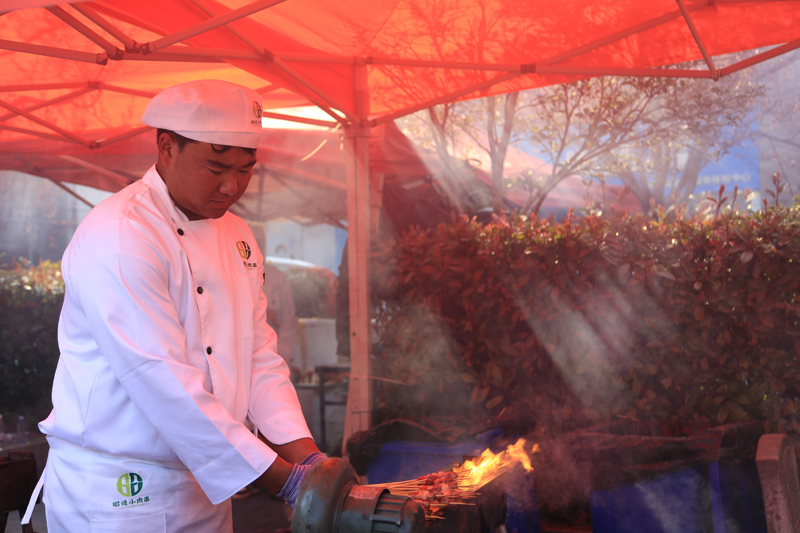 烤师聚精会神烤制着肉串