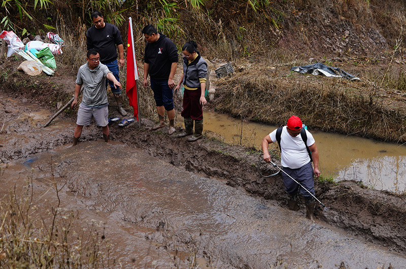 國家科技特派員團綠春成員徐雨然（左一）向當地工作人員和村民們示范水稻育秧關鍵技術。李建東攝