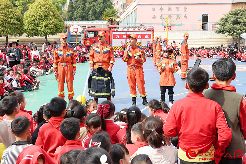 消防员为学生代表穿上灭火防护服。李丽摄