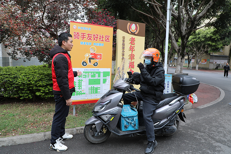 图为党员志愿者为骑手介绍骑手指引图。