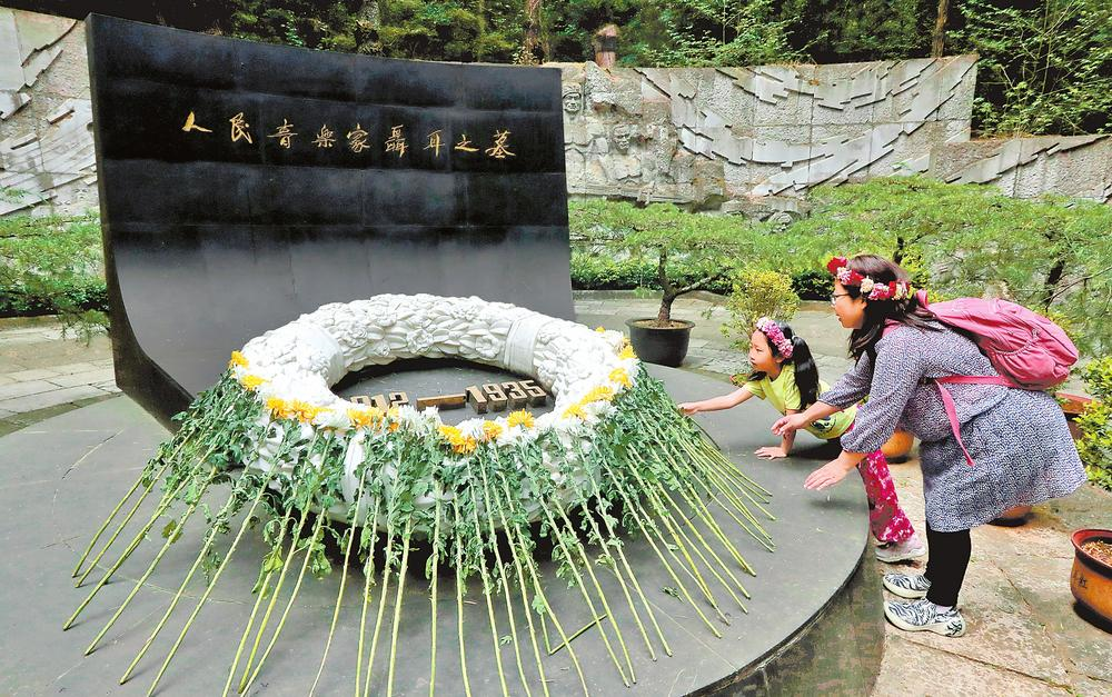 市民带着孩子在聂耳墓前献花。