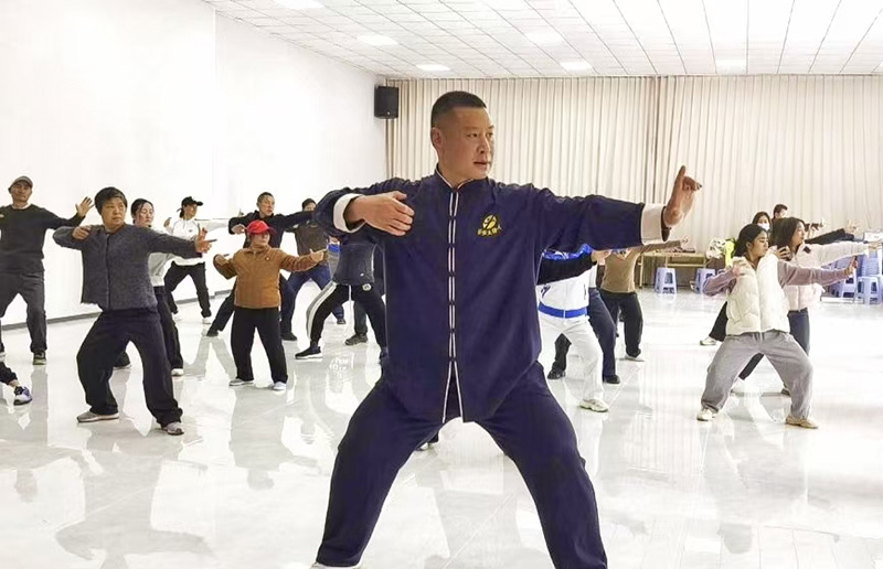 非遗传承人李培雄教练示范标准太极招式,学员们认真跟随练习(刘安红摄)