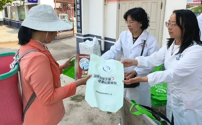 工作人員在集鎮核心區域設立血防宣傳咨詢點、懸挂主題橫幅、張貼主題海報，向過往群眾發放血吸虫病宣傳無紡袋等。