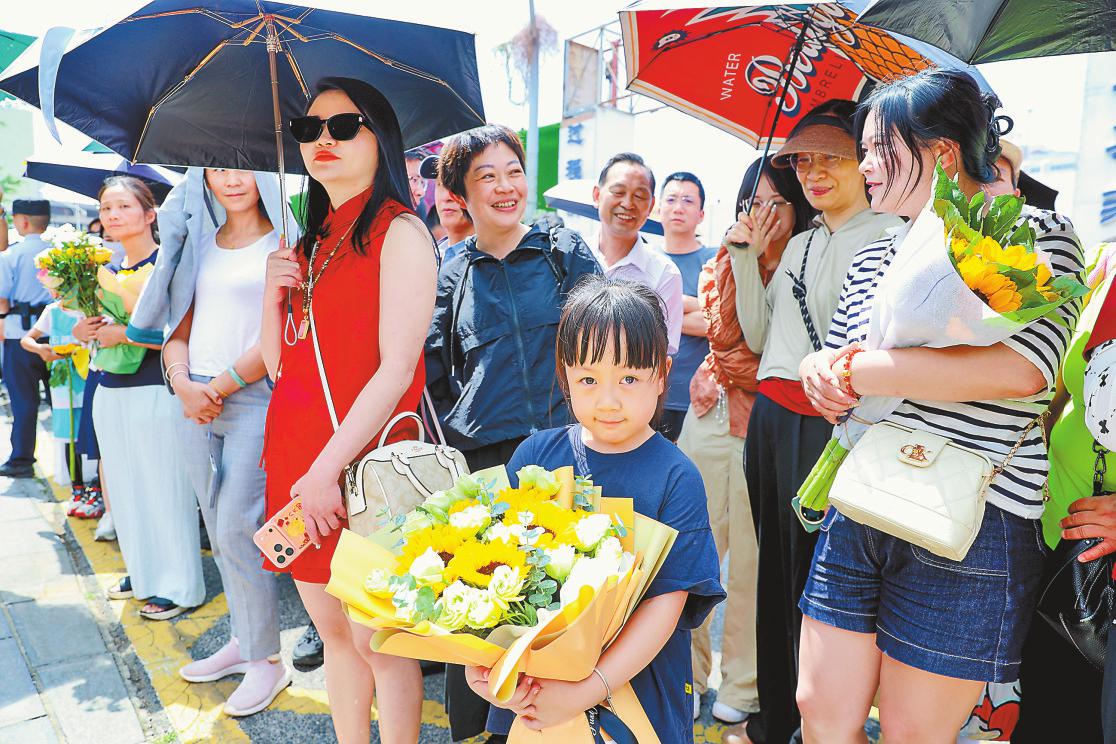 在昆一中考点外，小朋友怀抱花束静候家人。