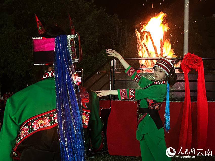 8月5日晚，一名彝族撒尼姑娘与2026云南石林火把节主火把合影。人民网记者 刘怡摄