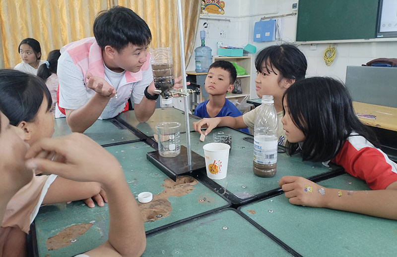 8月3号，在三桃乡新街村暑期儿童托管点，志愿者带领儿童开展“探玩”系列主题课程之“污水重生之旅”