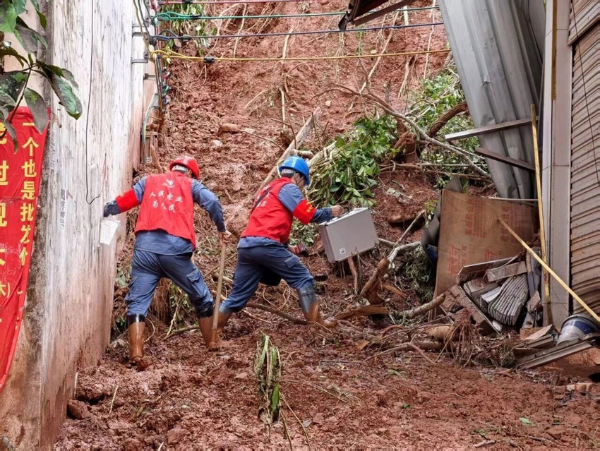 雲南電網西雙版納供電局工作人員在泥濘的道路中艱難前行。