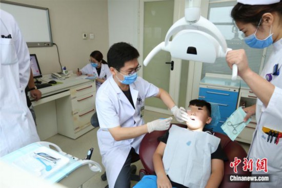 北京协和医院口腔科主任赵继志在为患者检查口腔。供图