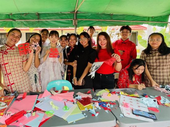 卡加延当地学生拿着剪纸与孔子学院老师合影。菲律宾大学孔子学院供图
