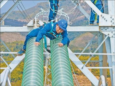 2月7日，工作人员在中老500千伏联网工程老挝段3号塔上检查绝缘子安装质量。张 强摄