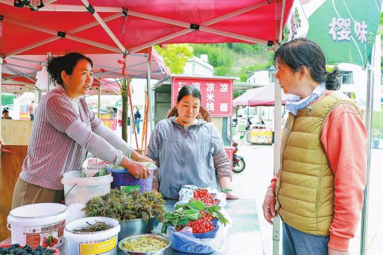 游客在七甸街道第十六届樱桃节集市上购买樱桃。